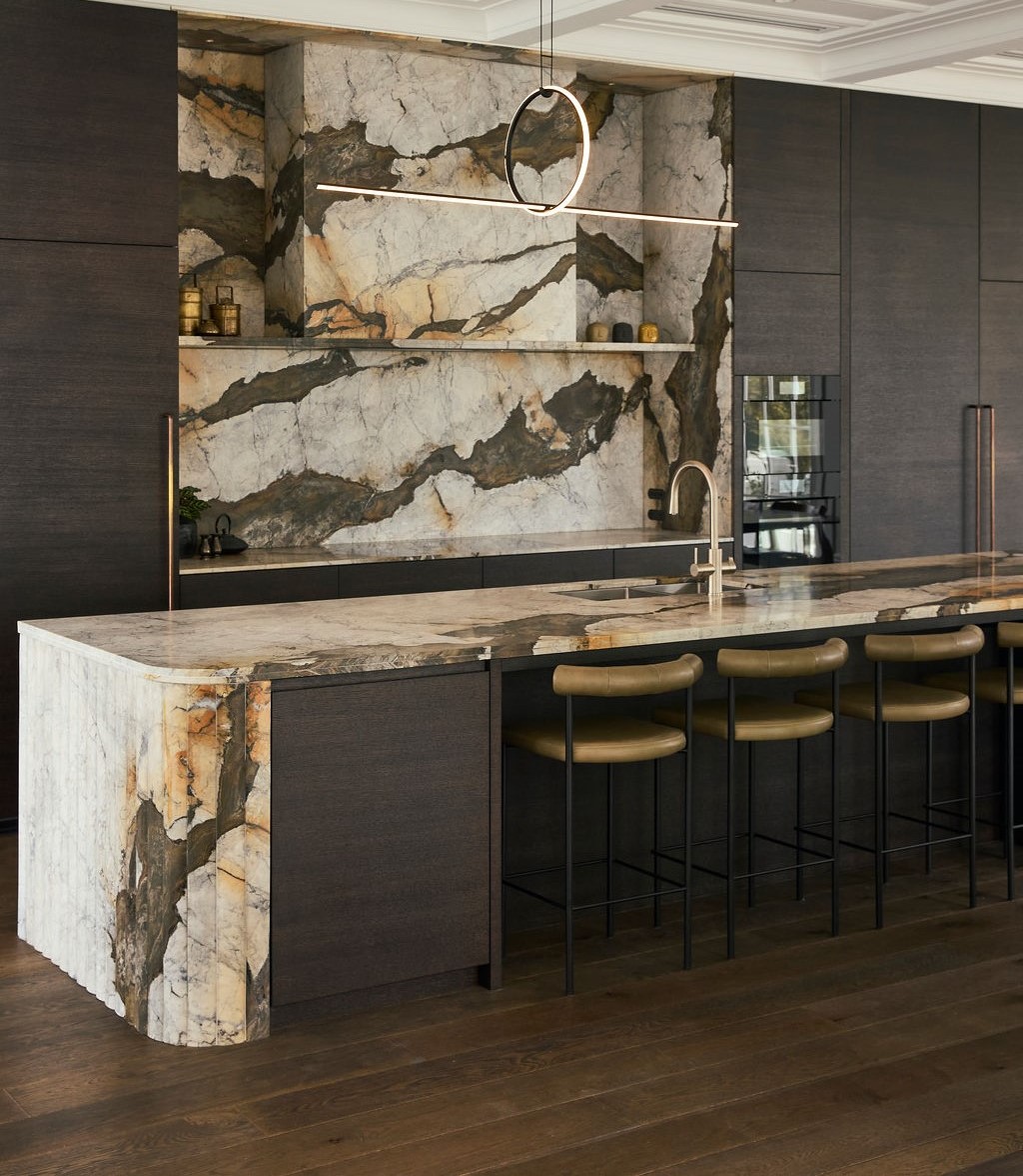 Iron white Calacatta marble kitchen island with multifaceted waterfall end and splashback and cladded rangehood