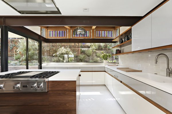 originally covered in colorful tile the kitchen received a monochromatic upgrade with white quartz countertops and new state of the art appliances