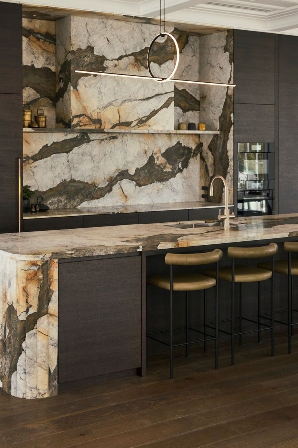 Iron white Calacatta marble kitchen island with multifaceted waterfall end and splashback and cladded rangehood