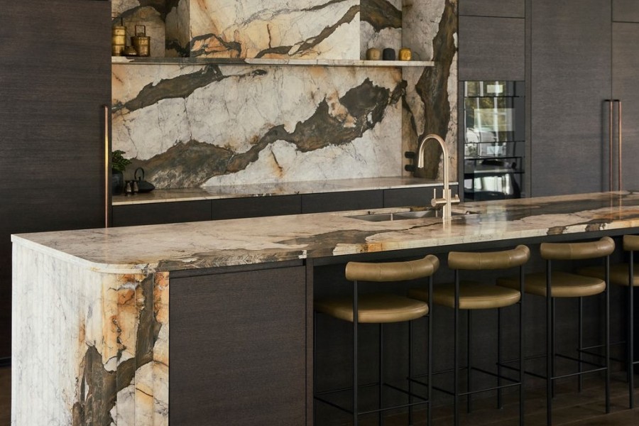 Iron white Calacatta marble kitchen island with multifaceted waterfall end and splashback and cladded rangehood